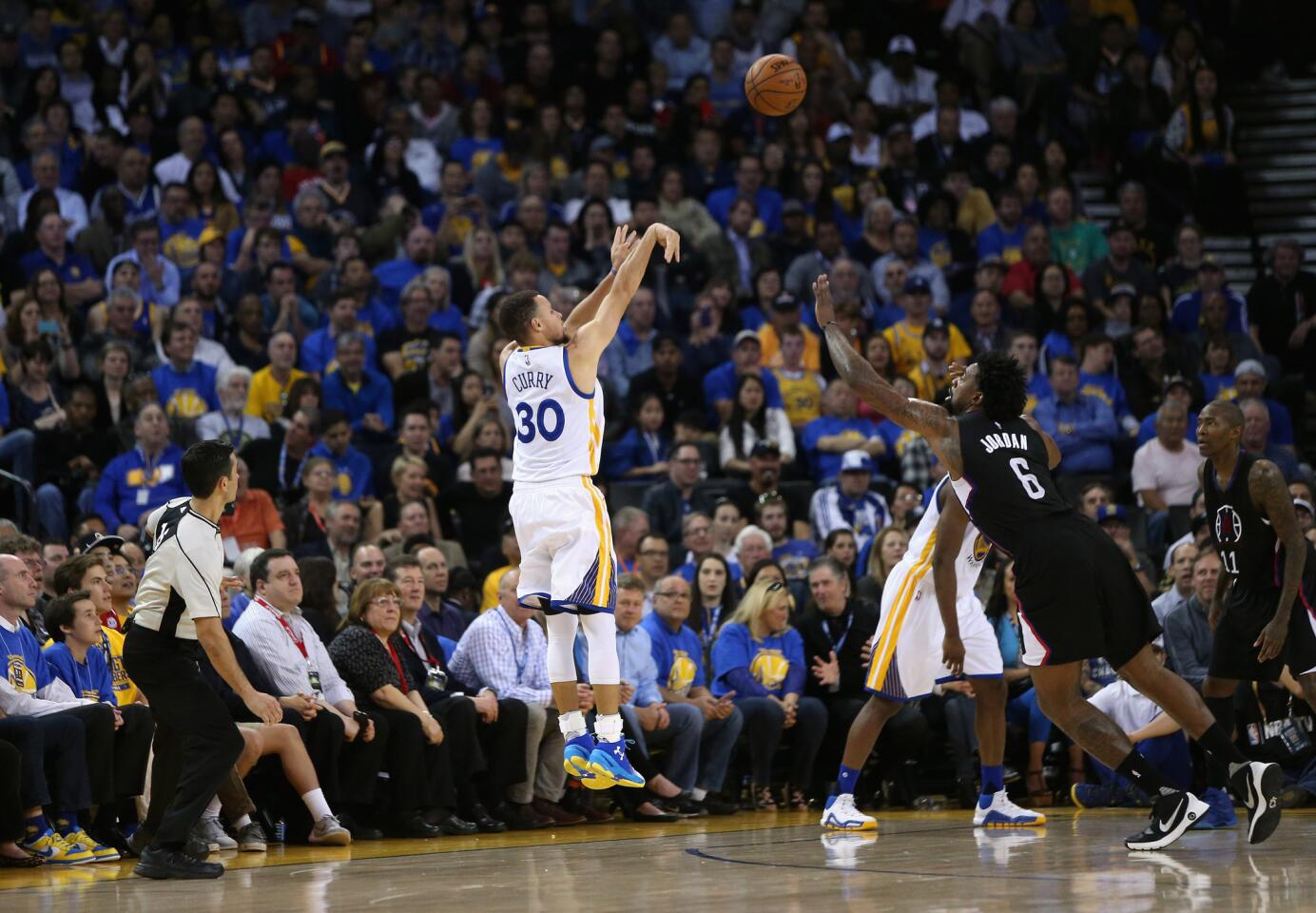 Warriors guard Stephen Curry (30) attempts a three-point shot over Clippers center DeAndre Jordan (6).