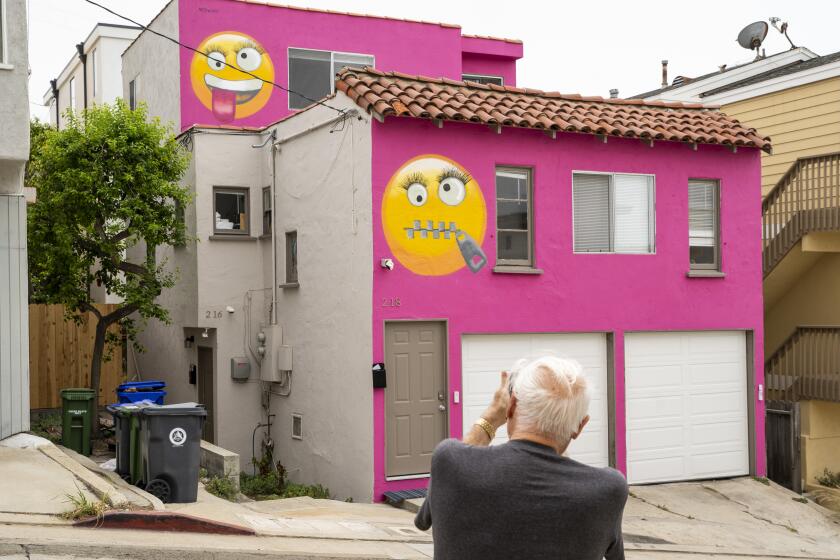 MANHATTAN BEACH, CALIF. - AUGUST 05: Bobby Gentry of Torrance, takes a photo of a pink house with emoji's painted on them, on 39th Street, owned by Kathyrn Kidd on Monday, Aug. 5, 2019 in Manhattan Beach, Calif. A city inspector found short-term renters on Kidd's property in May and Kidd was fined $4,000, as short-term rentals are illegal in Manhattan Beach. The emojis, with their zipped lips and big eyelashes, were Kidd’s response. (Kent Nishimura / Los Angeles Times) (Kent Nishimura / Los Angeles Times)