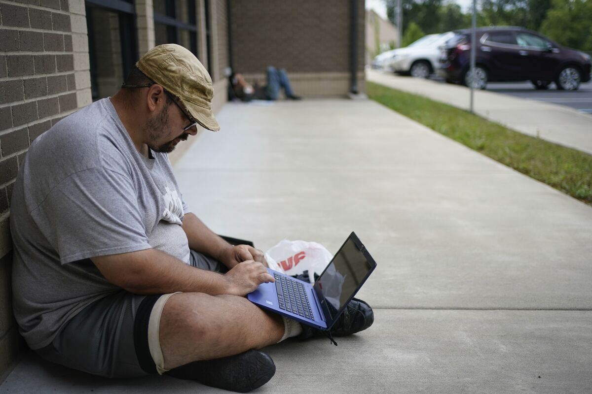 Barlow Mitchell sits outside the Lee County Public Library in Beattyville, Ky., to use the public Wi-Fi.