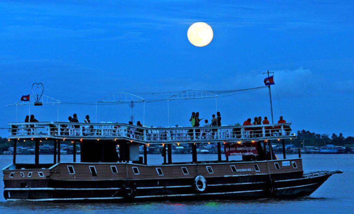 The moon rises as a tourist boat sails along the Mekong River in Phnom Penh, Cambodia.