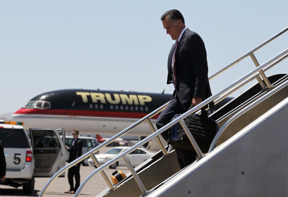 Mitt Romney walks off his campaign plane past Donald Trump's plane after landing in Las Vegas. The Obama campaign used the Romney-Trump meeting to try to associate the GOP candidate in voters' minds with the tycoon's more extreme views.