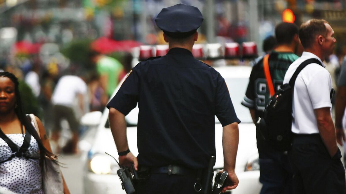 A New York City police officer stands in Times Square. An analysis of stops made under the Police Department's controversial "stop and frisk" policy reveals a bias against tall black men. Researchers confirmed this bias with a laboratory experiment.