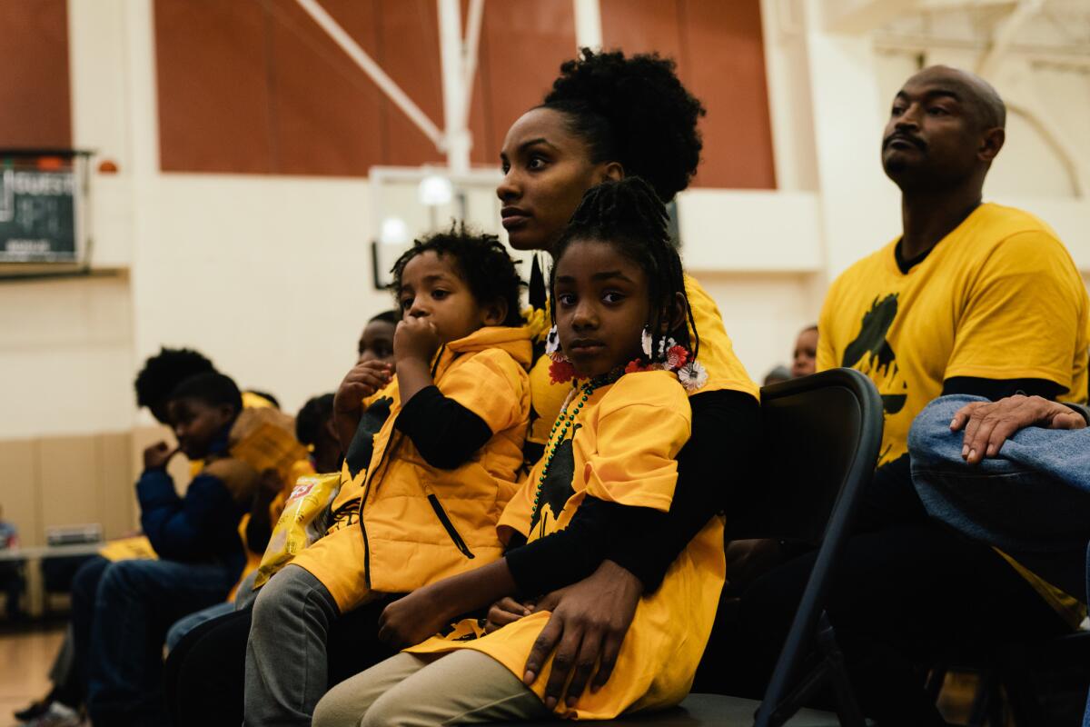 Toni Rochelle and her children Tatum Turner, 3, and Talia Turner, 6, wait for the start of the Oakland Unified School Board meeting at La Escuelita Elementary School in Oakland, Calif.