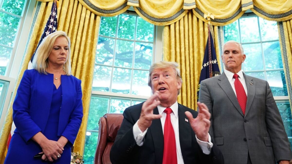 Homeland Security Secretary Kirstjen Nielsen and Vice President Mike Pence stand behind President Trump after he signed an executive order in the Oval Office on Wednesday to end the separation of migrant families at the border.