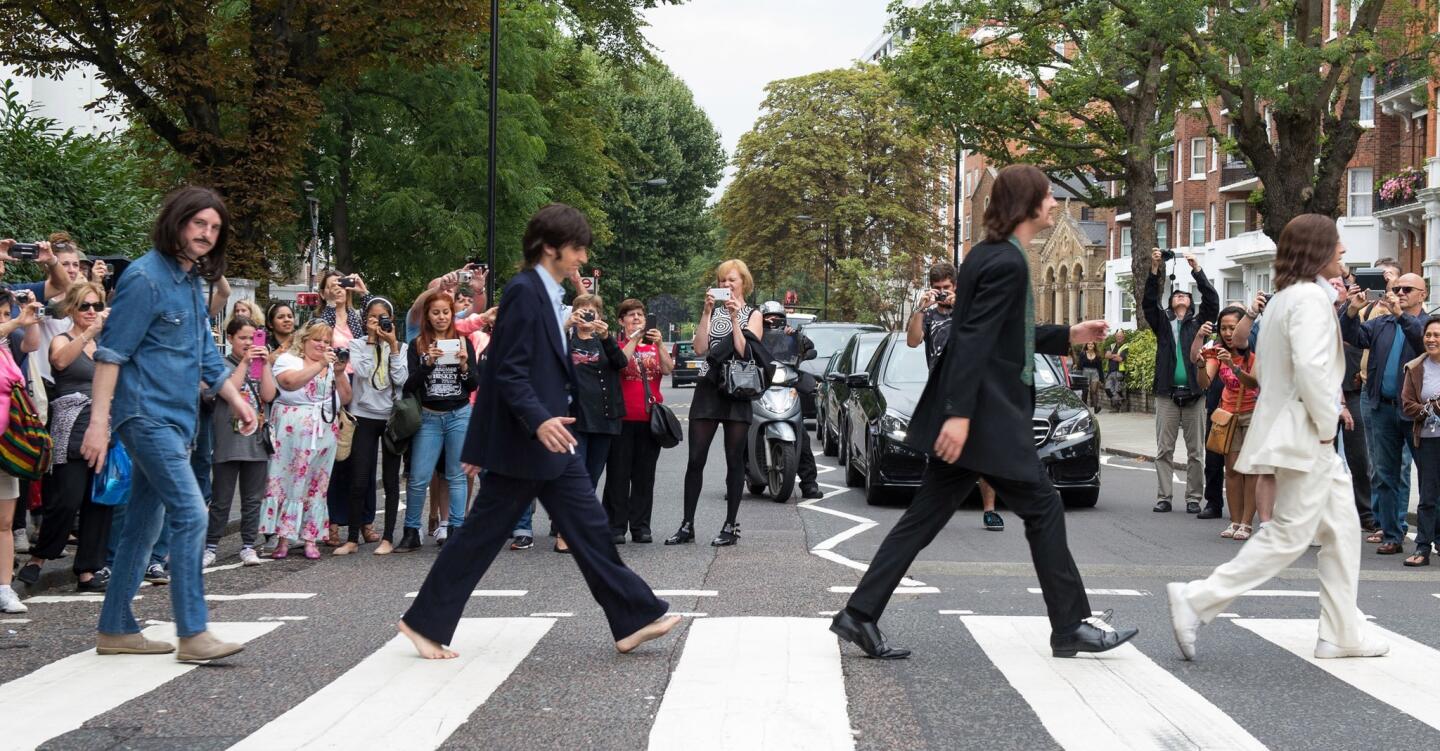 The cast of the West End show "Let It Be" cross the street outside Abbey Road Studios in London to re-create the Beatles' album photo, which was shot Aug. 8, 1969.