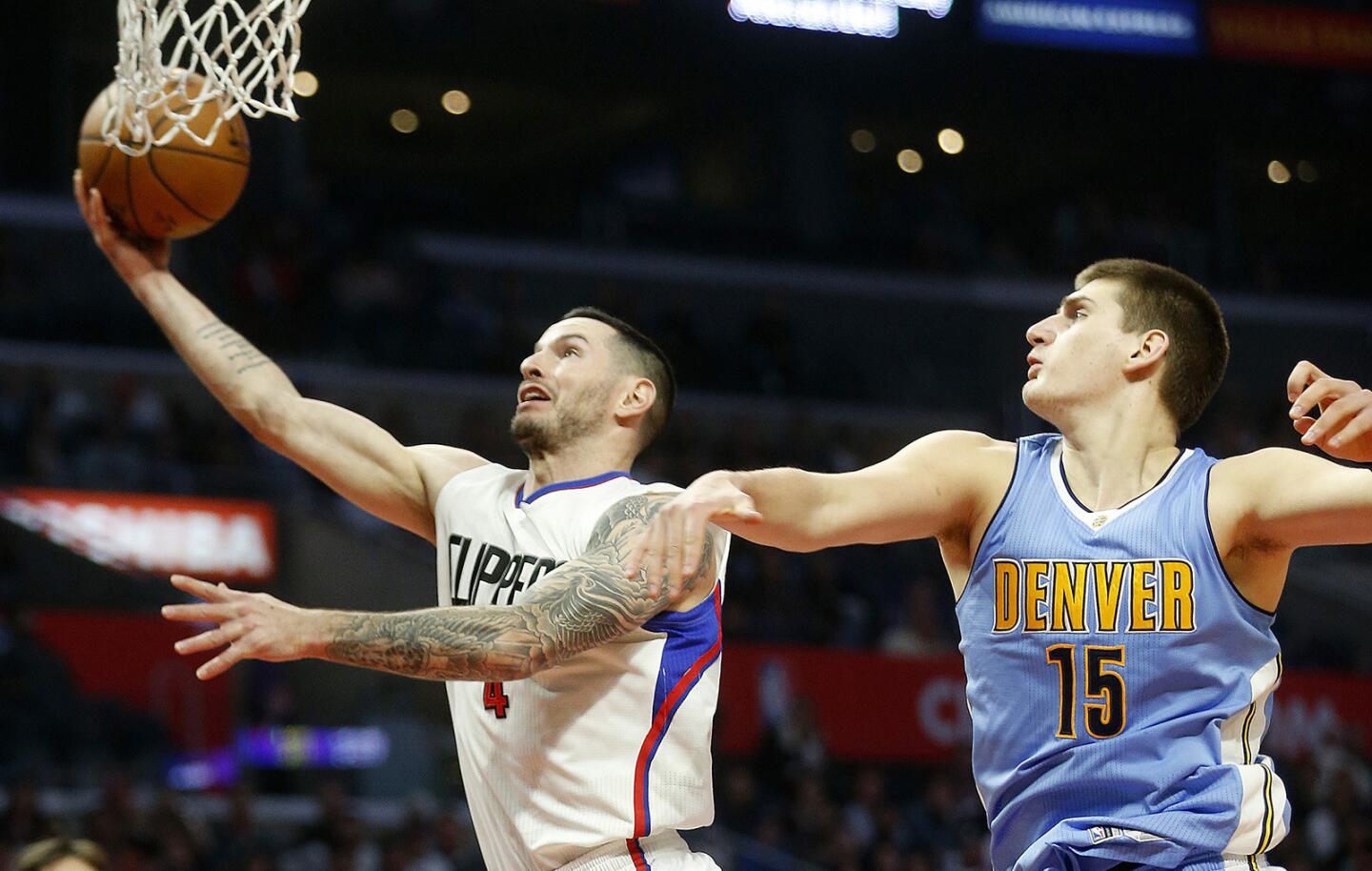 Clippers guard J.J. Redick (4) drives to the basket while being defended by Denver Nuggets forward Nikola Jokic (15) in the second quarter at Staples Center.