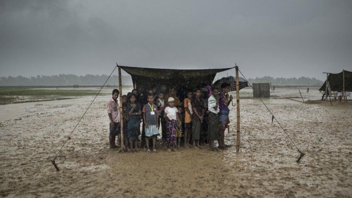 Rohingya Muslim refugees take shelter from the rain during a food distribution at Nayapara refugee camp in Bangladesh in October 2017.