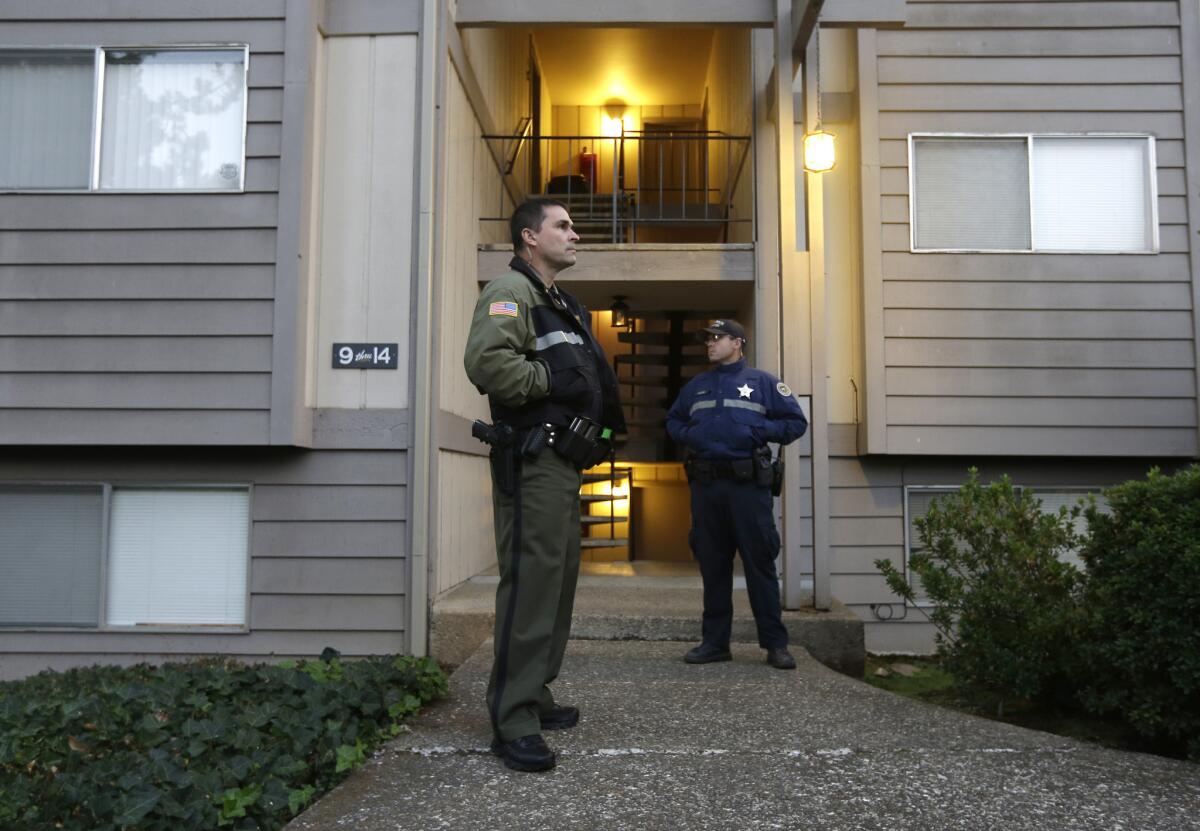 Douglas County Deputy Sheriff Greg Kennerly, left, and Oregon State Trooper Tom Willis stand guard outside the apartment building where alleged Umpqua Community College gunman Chris Harper Mercer lived near Roseburg, Ore.