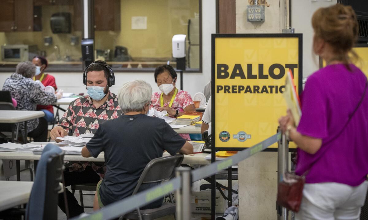 A poll watcher observes election workers next to a sign that says "Ballot preparation."