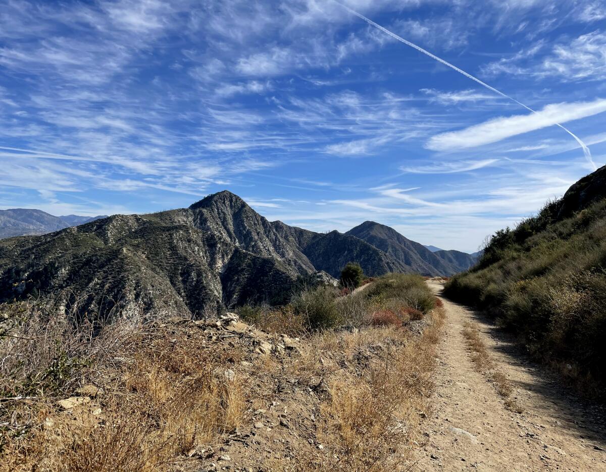 View of a hiking trail through mountain peaks and blue sky