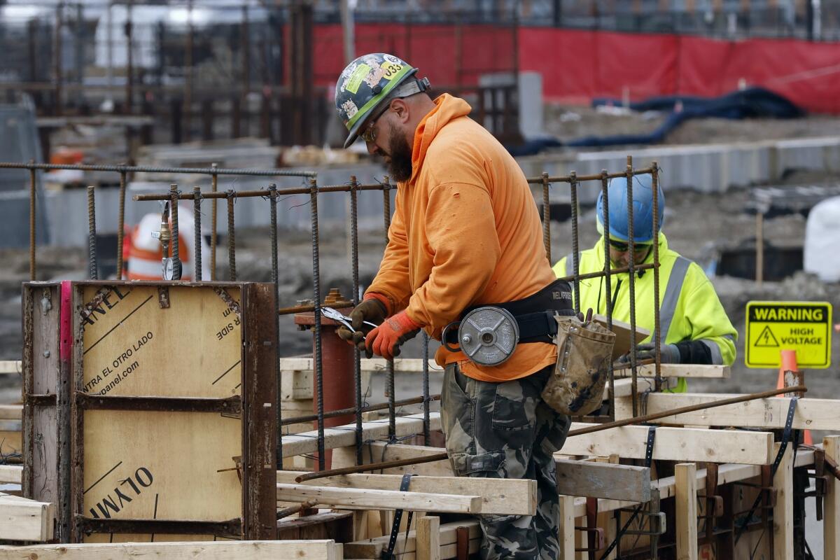 A construction worker wires rebar for a foundation.