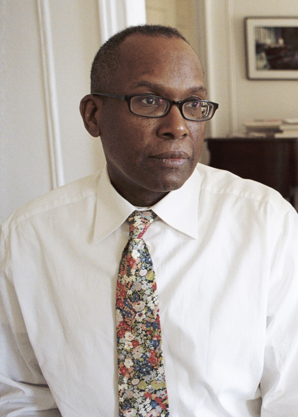 A black man wearing a white shirt and floral tie 