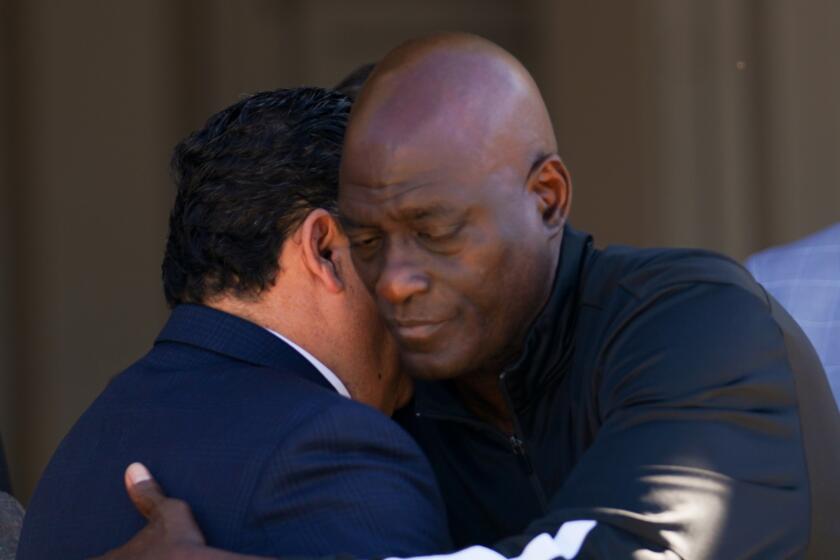 Michael Cooper, right, hugs a Pasadena Mayor Victor M. Gordo 