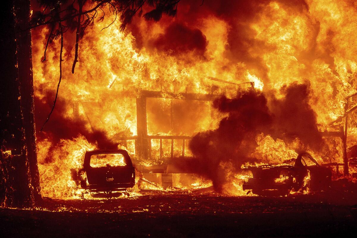 Fire envelops a house and car.