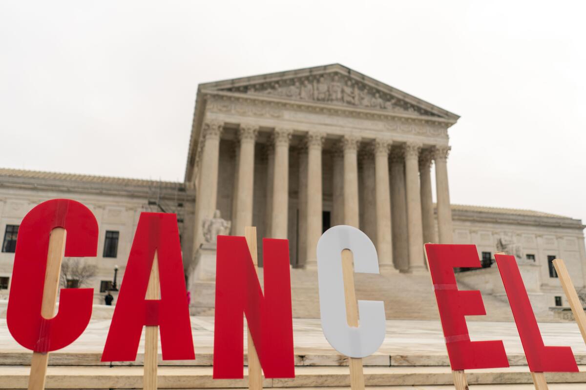 Picket signs spell out "cancel" in front of the the Supreme Court