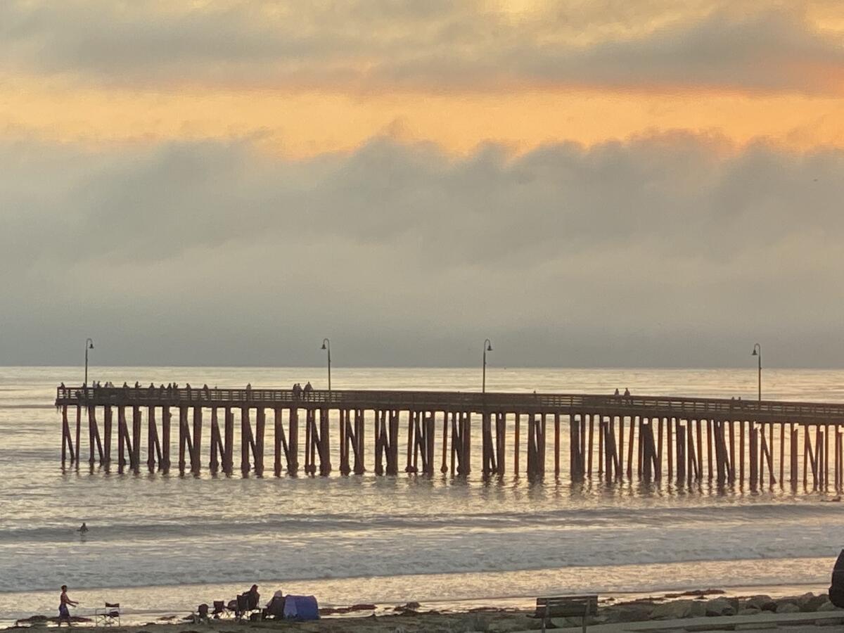 A pier seen against a golden sky with clouds 