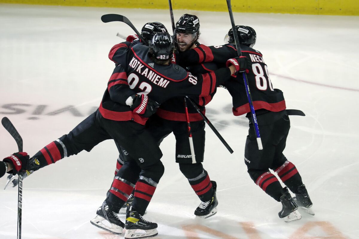 Carolina Hurricanes defenseman Ian Cole (28) celebrates his overtime goal against the New York Rangers with Jesperi Kotkaniemi (82), Martin Necas (88) and Brendan Smith (7) during Game 1 of an NHL hockey Stanley Cup second-round playoff series Wednesday, May 18, 2022 in Raleigh, N.C. (AP Photo/Chris Seward)
