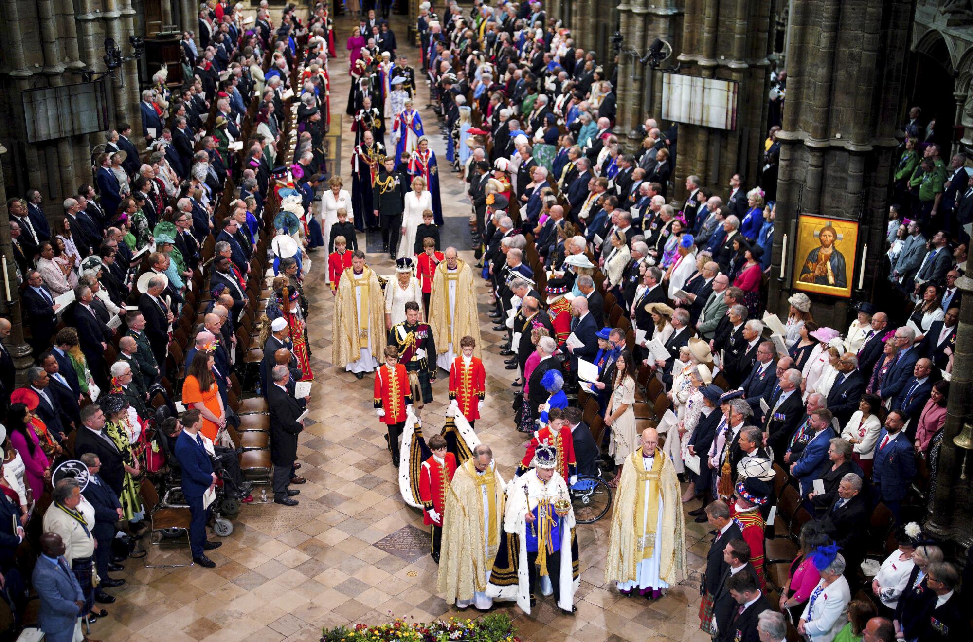 King Charles III, wearing the Imperial State Crown, followed by Queen Camilla, leaves Westminster Abbey 