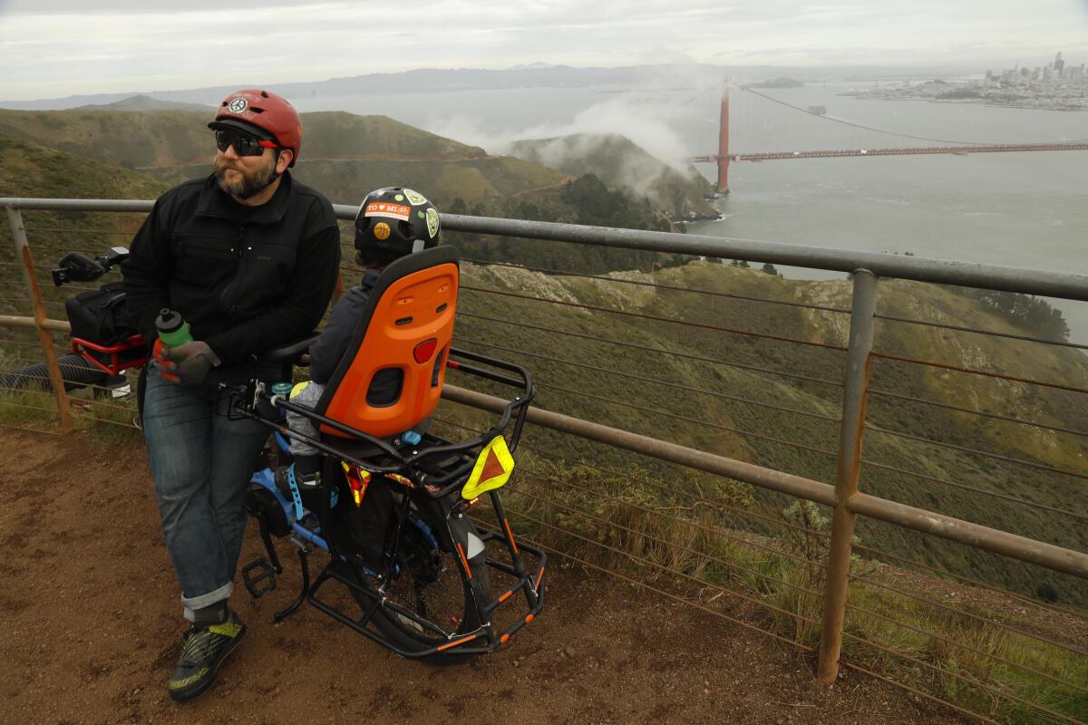 San Francisco resident Matt Dove, 41, and his son Elijah, 3, take a break from riding their e-bike at Hawk Hill overlooking the Golden Gate Bridge in Marin County.