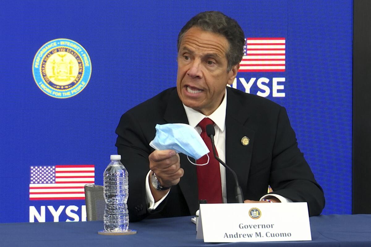 New York Gov. Andrew Cuomo holds a face mask while talking to the media at the New York Stock Exchange in March.
