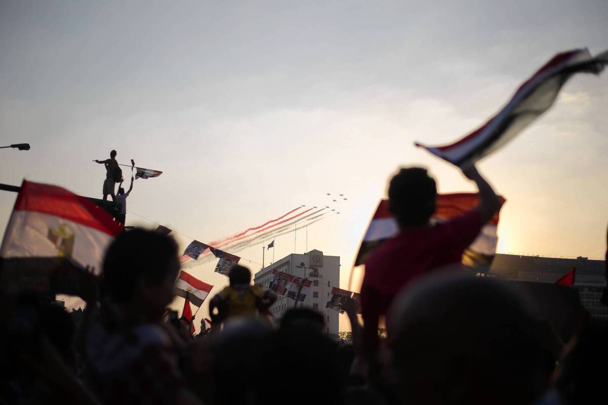 Egyptians wave the national flag as military planes fly over Tahrir Square in Cairo, a day after the coup that ousted President Mohamed Morsi.