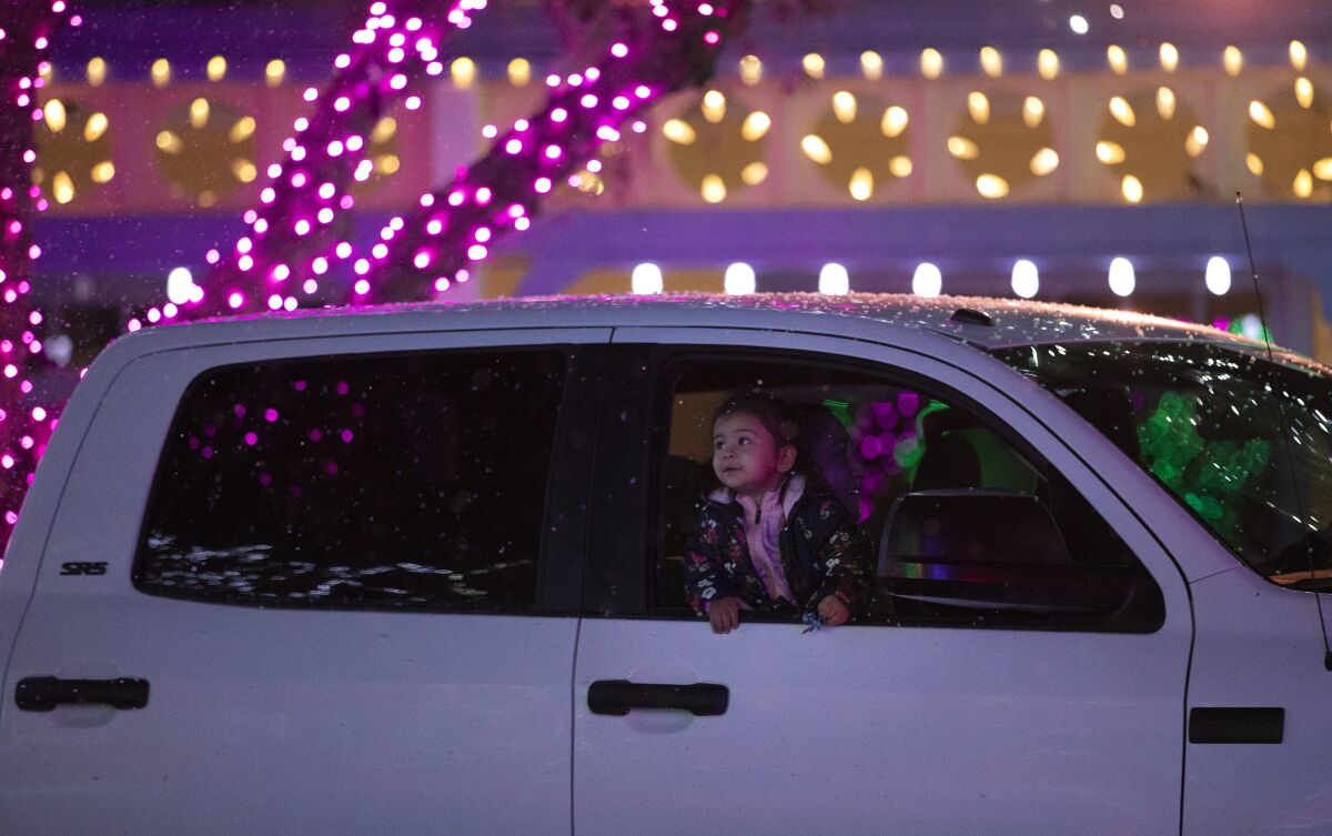 A child in a car looks at fake snowfall and colorful lights at Six Flags Magic Mountain