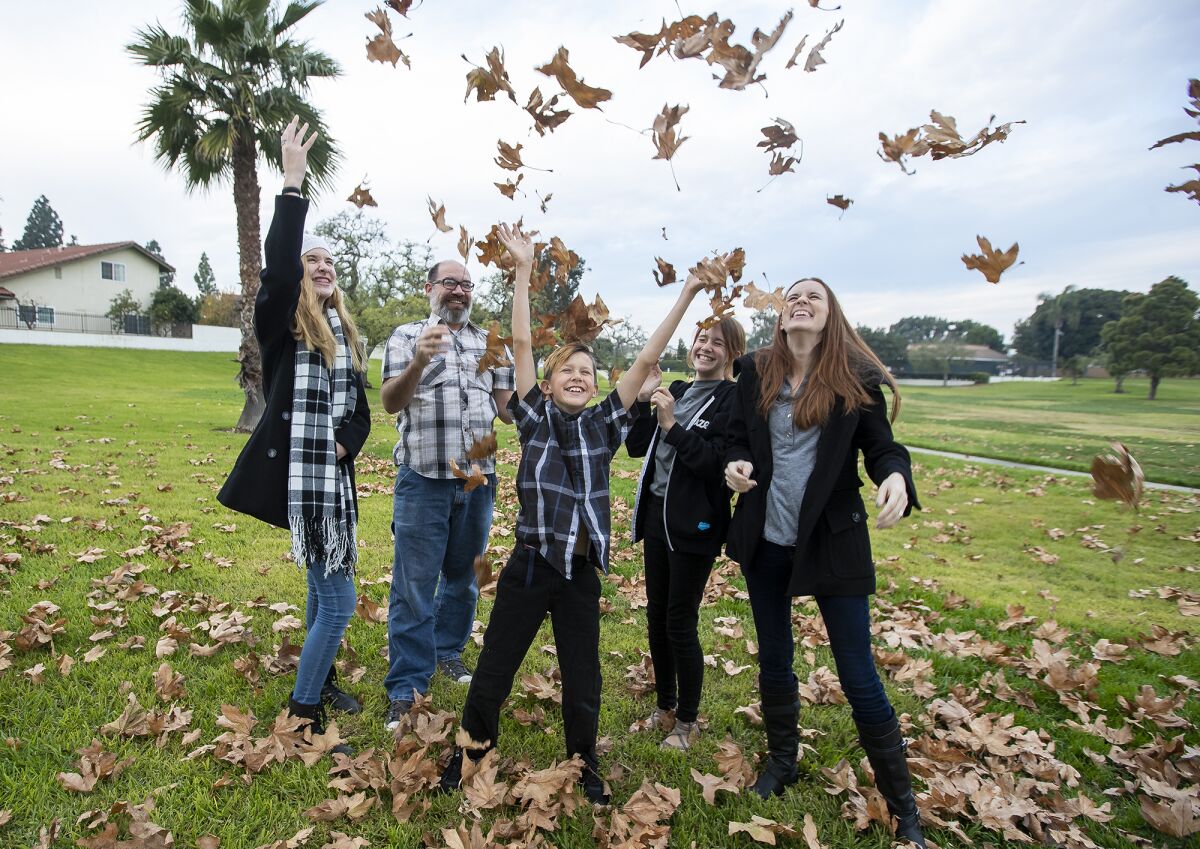 The Davis family throw leaves in the air at Green Valley Park on Monday.