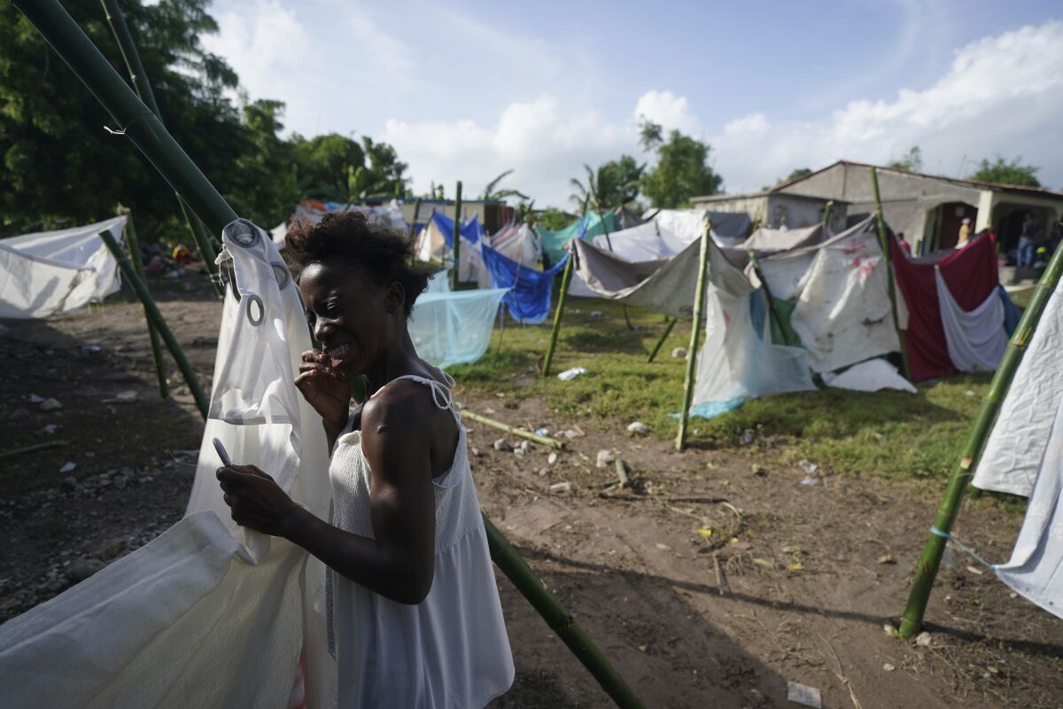 Una mujer se limpia los dientes con hilo dental el miércoles 18 de agosto de 2021 en medio de tiendas de campaña improvisadas que fueron colocadas por residentes desplazados en Les Cayes, Haití, luego del sismo de magnitud 7,2 que sacudió a la nación caribeña. (AP Foto/Fernando Llano)