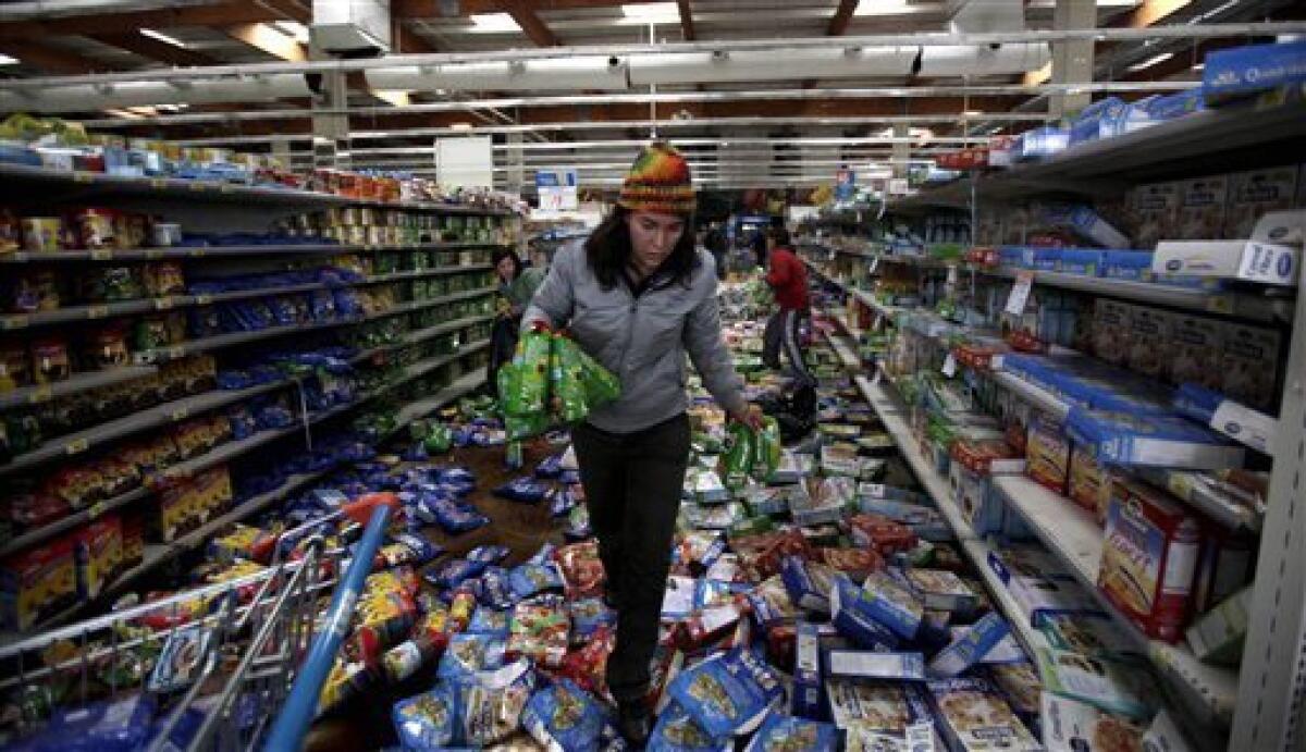 A woman carries goods during looting a supermarket in Concepcion, Chile, Sunday, Feb. 28, 2010. A 8.8-magnitude earthquake hit Chile early Saturday. (AP Photo/ Natacha Pisarenko)