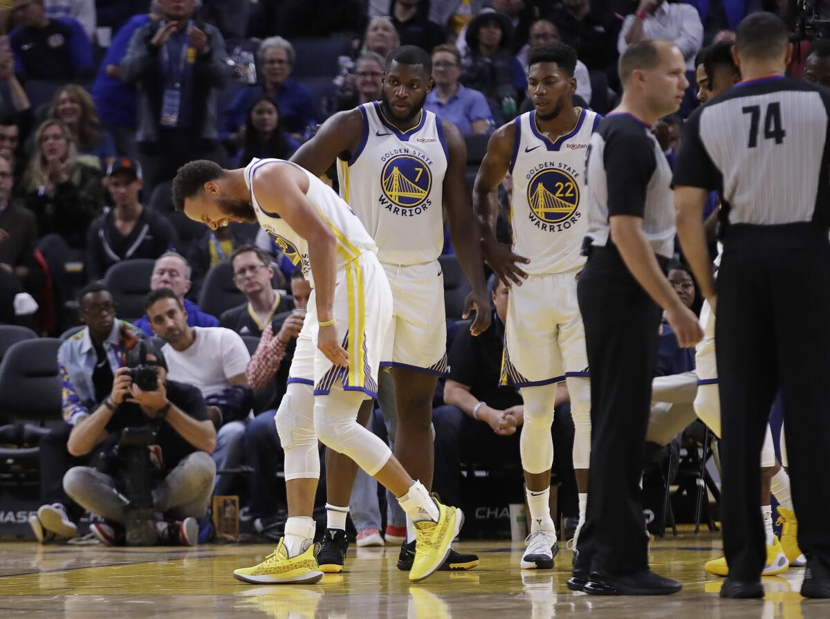 Warriors guard Stephen Curry grimaces after injuring his left hand during a game against the Suns.
