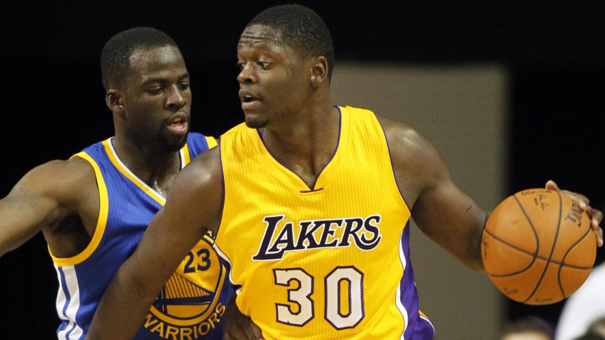 Lakers forward Julius Randle backs in against Golden State Warriors forward Draymond Green during a preseason game in October 2014.