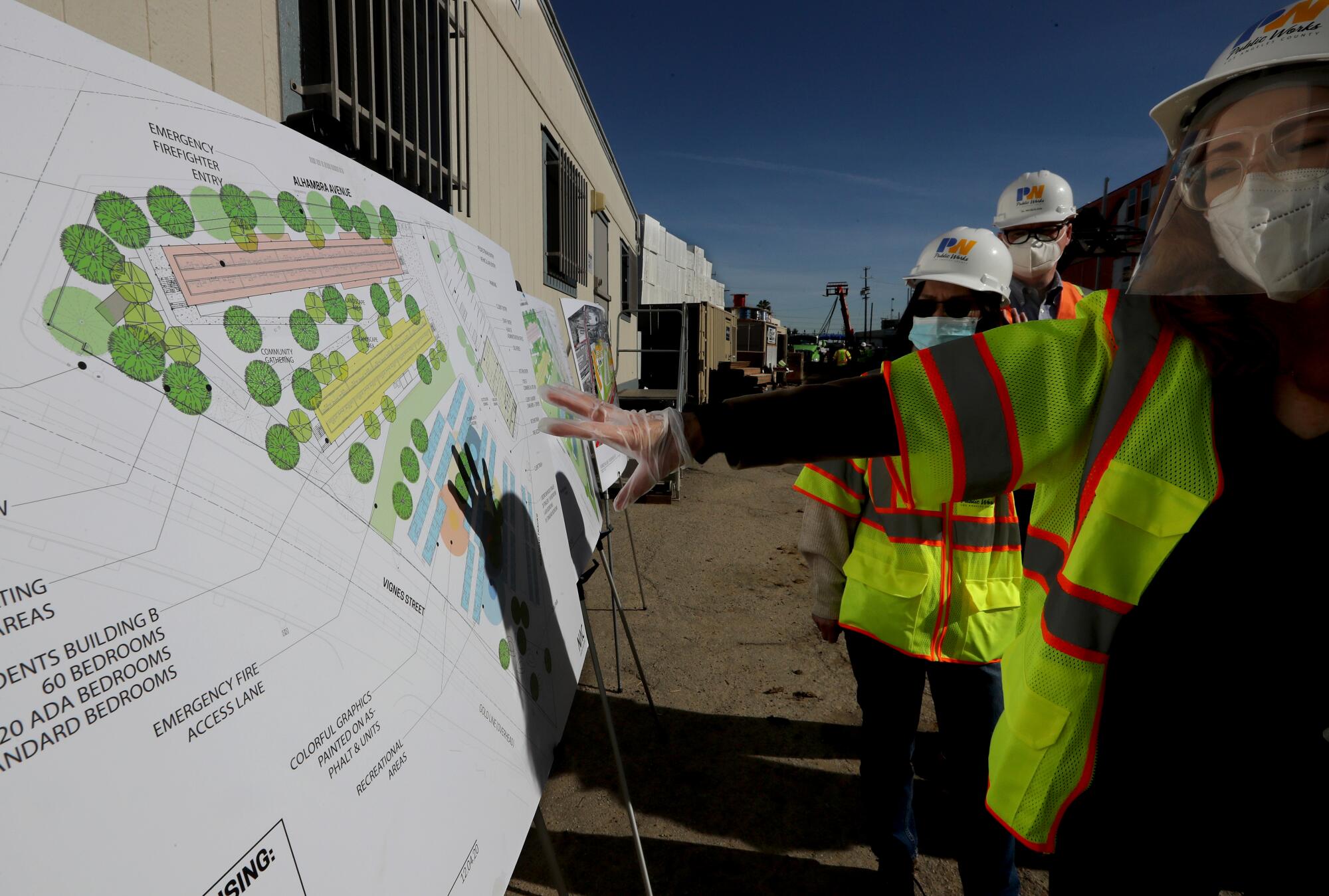 L.A. County officials and contractors look at plans of the homeless housing project.