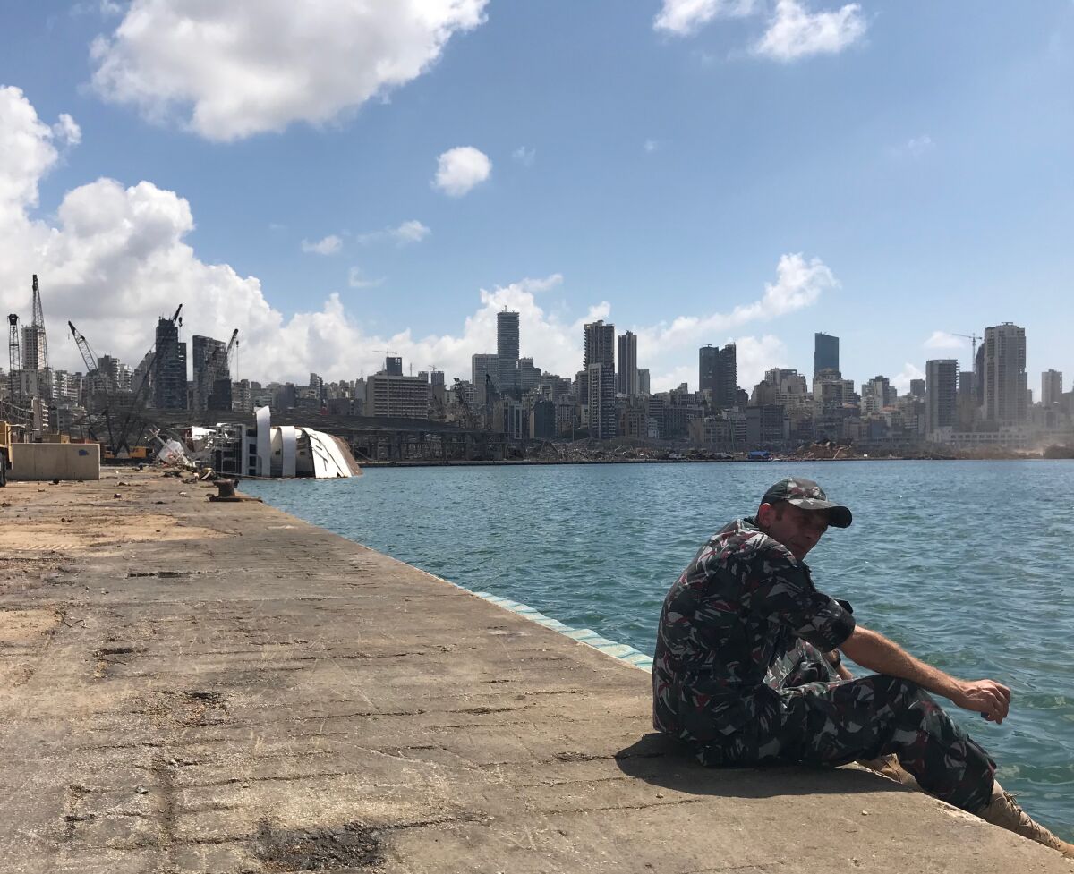 A security officer keeps watch in Beirut's port. The capsized Orient Queen cruise ship is seen in the background.