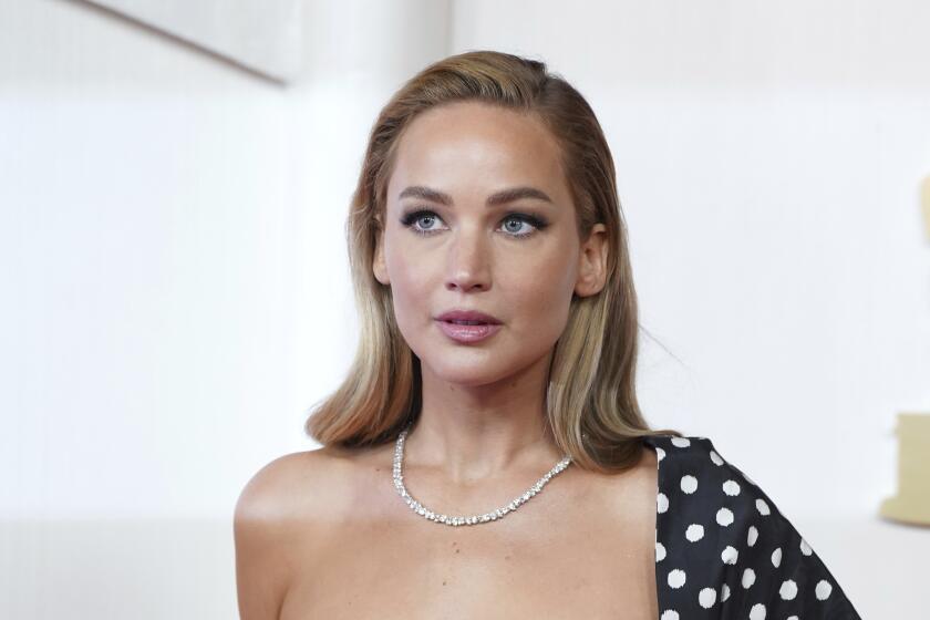 Jennifer Lawrence looks up while wearing a diamond necklace and one-shoulder polka dot gown