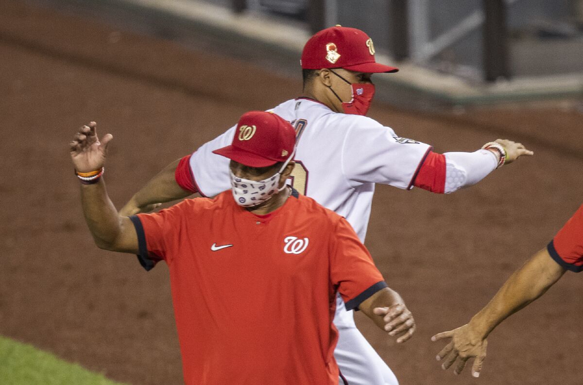 Washington Nationals' Juan Soto back, celebrates with manager Dave Martinez, after the Nationals defeated the New York Mets 5-3 a baseball game in Washington, Tuesday, Aug. 4, 2020. (AP Photo/Manuel Balce Ceneta)