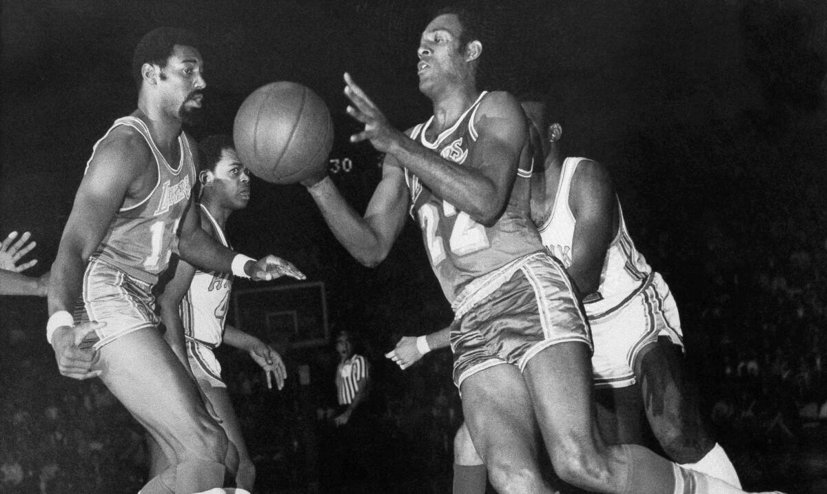 Lakers center Wilt Chamberlain, left, passes to Elgin Baylor during a game against the Atlanta Hawks on Jan. 24, 1969.