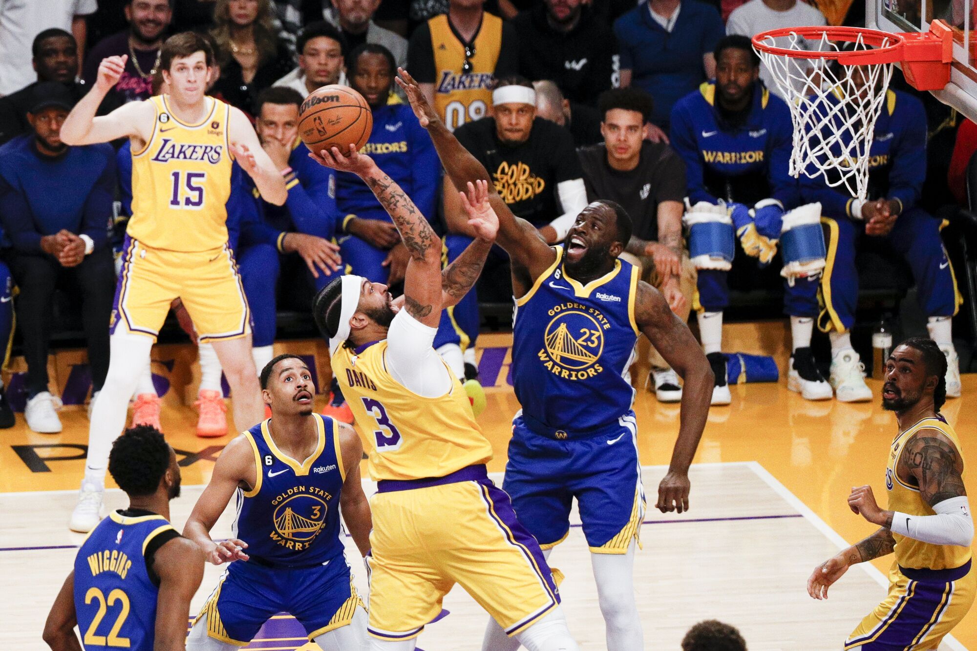 Lakers forward Anthony Davis, center, is fouled by Warriors forward Draymond Green, right, on a shot attempt in the lane.