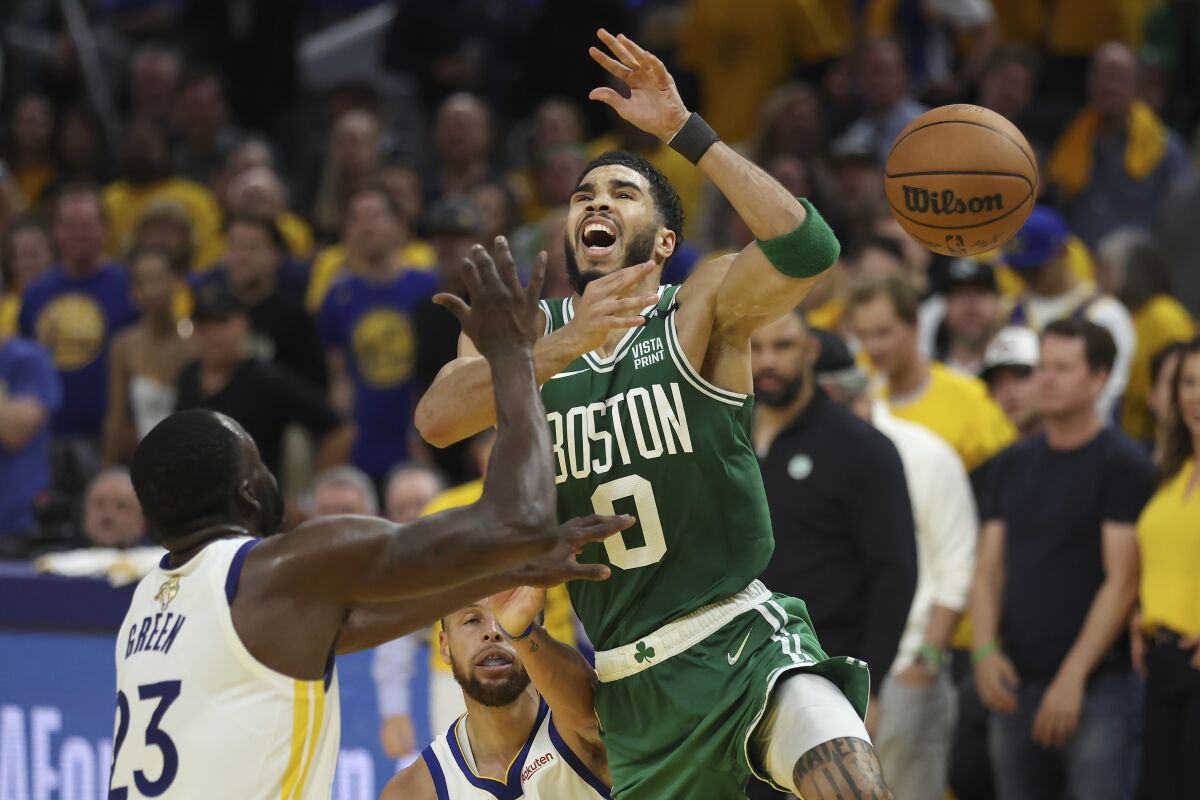 Boston Celtics forward Jayson Tatum (0) loses the ball while being defended by Golden State Warriors forward Draymond Green (23) and guard Stephen Curry during the second half of Game 1 of basketball's NBA Finals in San Francisco, Sunday, June 5, 2022. (AP Photo/Jed Jacobsohn)