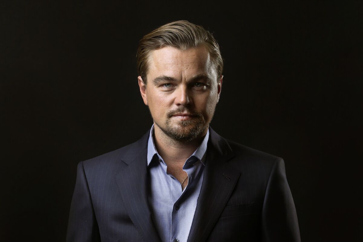 Leonardo DiCaprio in a dark suit against a dark background