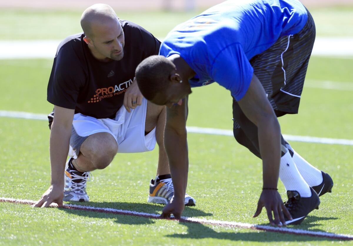 Marqise Lee, an All-American receiver while at USC, works on his starting form for the 40-yard dash with Proactive Sports Performance trainer Ryan Capretta during a training session at Laguna Hills High.