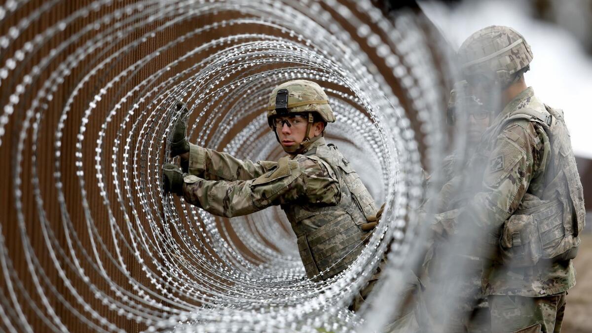 Alexander Gomez, a specialist horizontal construction engineer with the U.S. Army, installs coils of concertina wire near the banks of the Rio Grande along the U.S. border with Mexico in Brownsville, Texas, on Nov. 13, 2018.