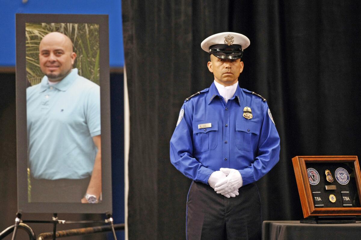 A Transportation Security Administration officer stands in front of a portrait of slain TSA officer Gerardo Hernandez during his public memorial after he was shot during a 2013 rampage by Paul Ciancia. Three others were wounded before Ciancia was shot by police.