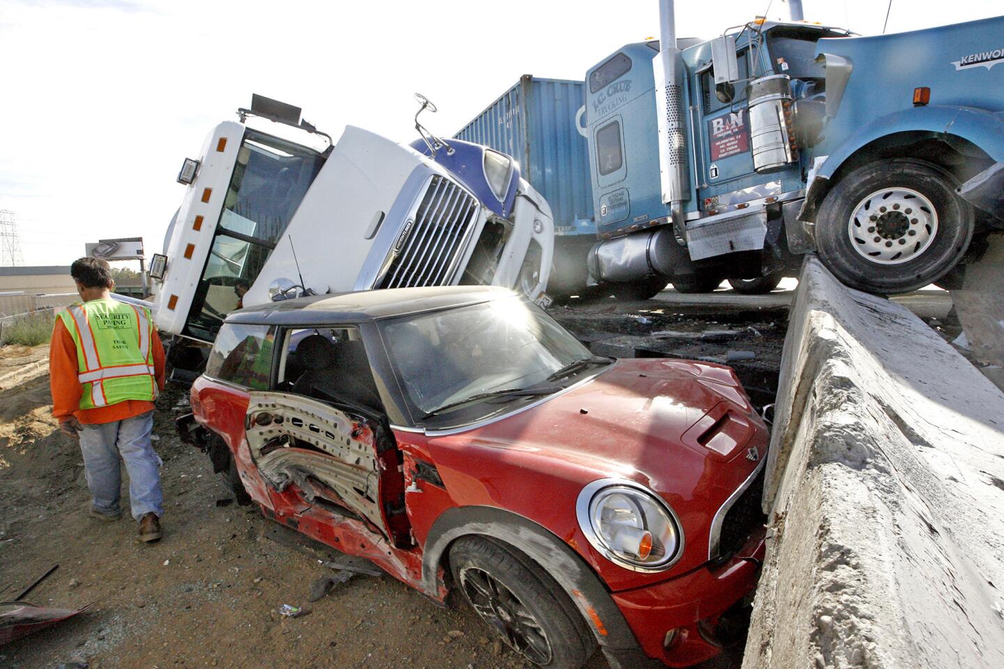 A construction worker walks past a crash on the northbound I-5 freeway before Western Ave. involving two big rigs and a Mini Cooper on Wednesday, November 14, 2012. There were no injuries, although one big rig, a oil tanker, was leaking waste oil. (Roger Wilson/Staff Photographer)