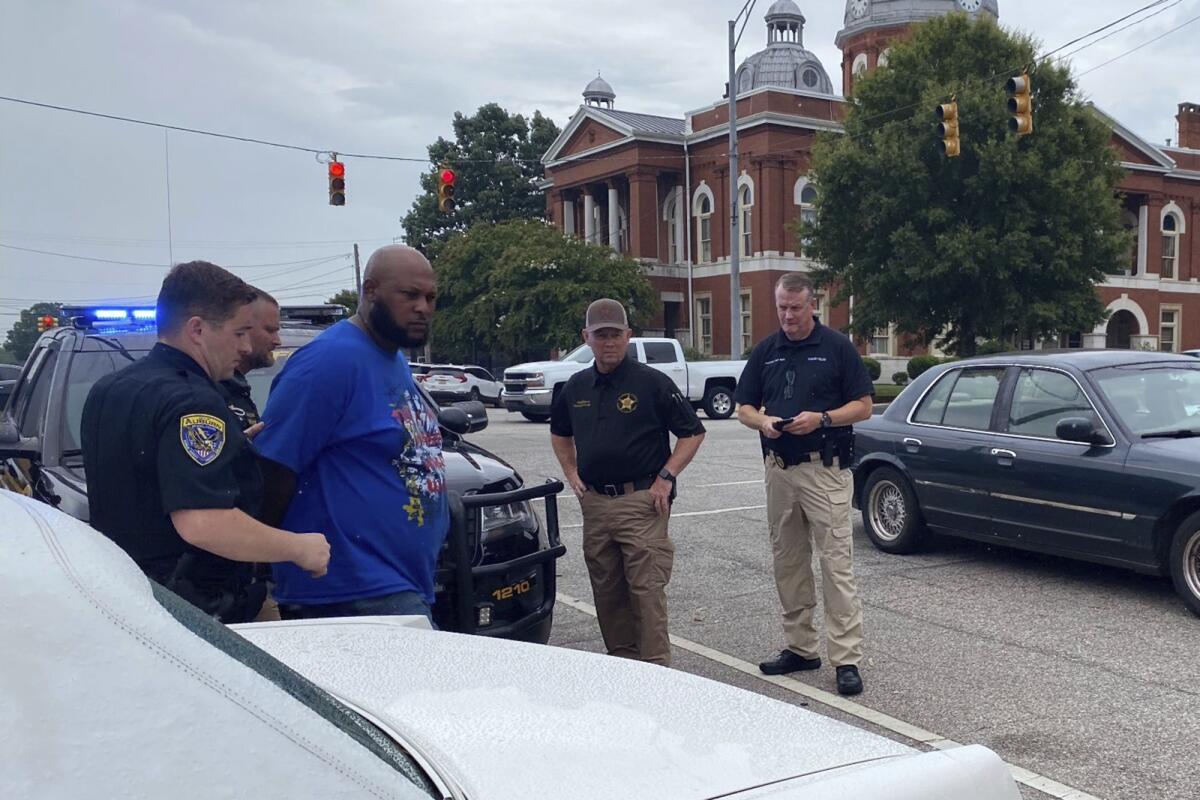 This photo provided by Troup County Sheriff's Office police take Jerel Raphael Brown into custody on Aug. 17, 2022 in LaFayette, Ala. Brown, 39, of Montgomery was arrested without incident Wednesday near the courthouse in LaFayette with more than 2,000 rounds of ammunition and an alarming number of firearms in his 1996 white Cadillac Fleetwood, police said. (Troup County Sheriff's Office via AP)