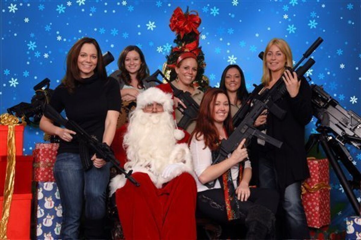 This undated photo provided by the Scottsdale Gun Club shows people posing with Santa Claus and several automatic weapons at the Scottsdale, Ariz. club. Ron Kennedy, general manager of the gun club, says the business got the idea for the photo op last year when a club member happened to come in dressed as Santa and other members wanted their picture taken while they were holding their guns. He says people have used the photos for Christmas cards and Facebook posts. (AP Photo/Scottsdale Gun Club, Gordon Murray)