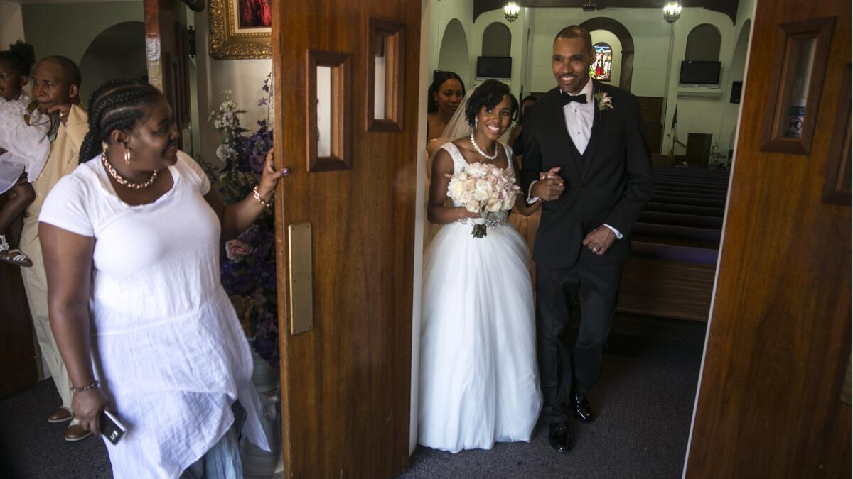 Jamie Nieto and his bride, Shevon, walk together after marrying at the Greater Christ Temple Apostolic Church.
