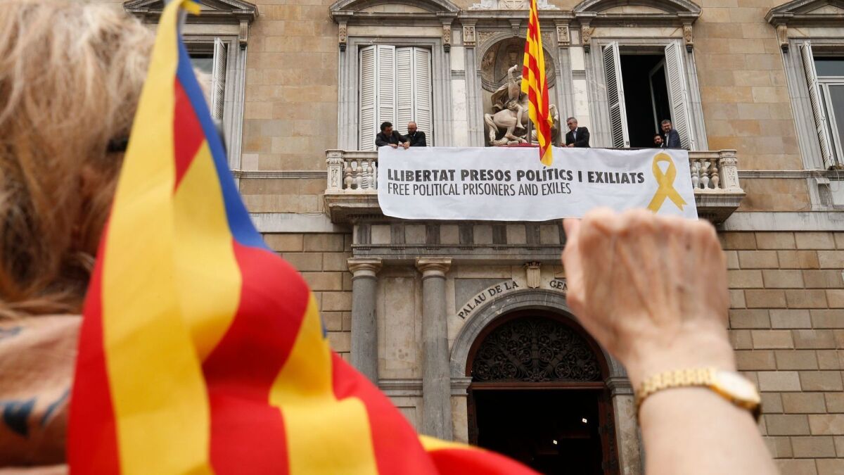 A supporter raises a fist and waves the Estelada flag as a banner reading "Free political prisoners and those exiled" hangs from the balcony of the Generalitat Palace in Barcelona after the swearing-in of the new Catalan government on June 2, 2018.