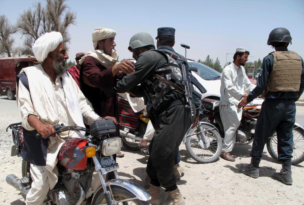 Afghan police officers search commuters at a checkpoint in Helmand province on June 25. A Taliban offensive in its fourth day in the southeastern region has killed scores of civilians and fighters.