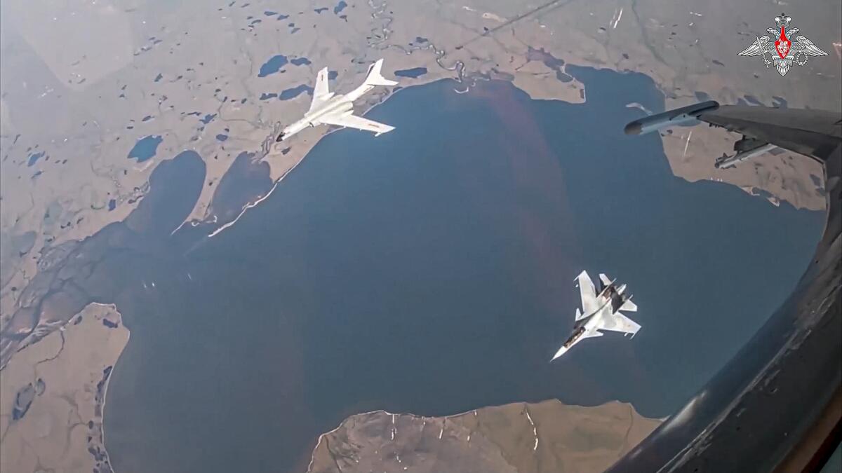 High-altitude view of a Chinese H-6K long-range bomber, upper left, escorted by a Russian Su-30 fighter.