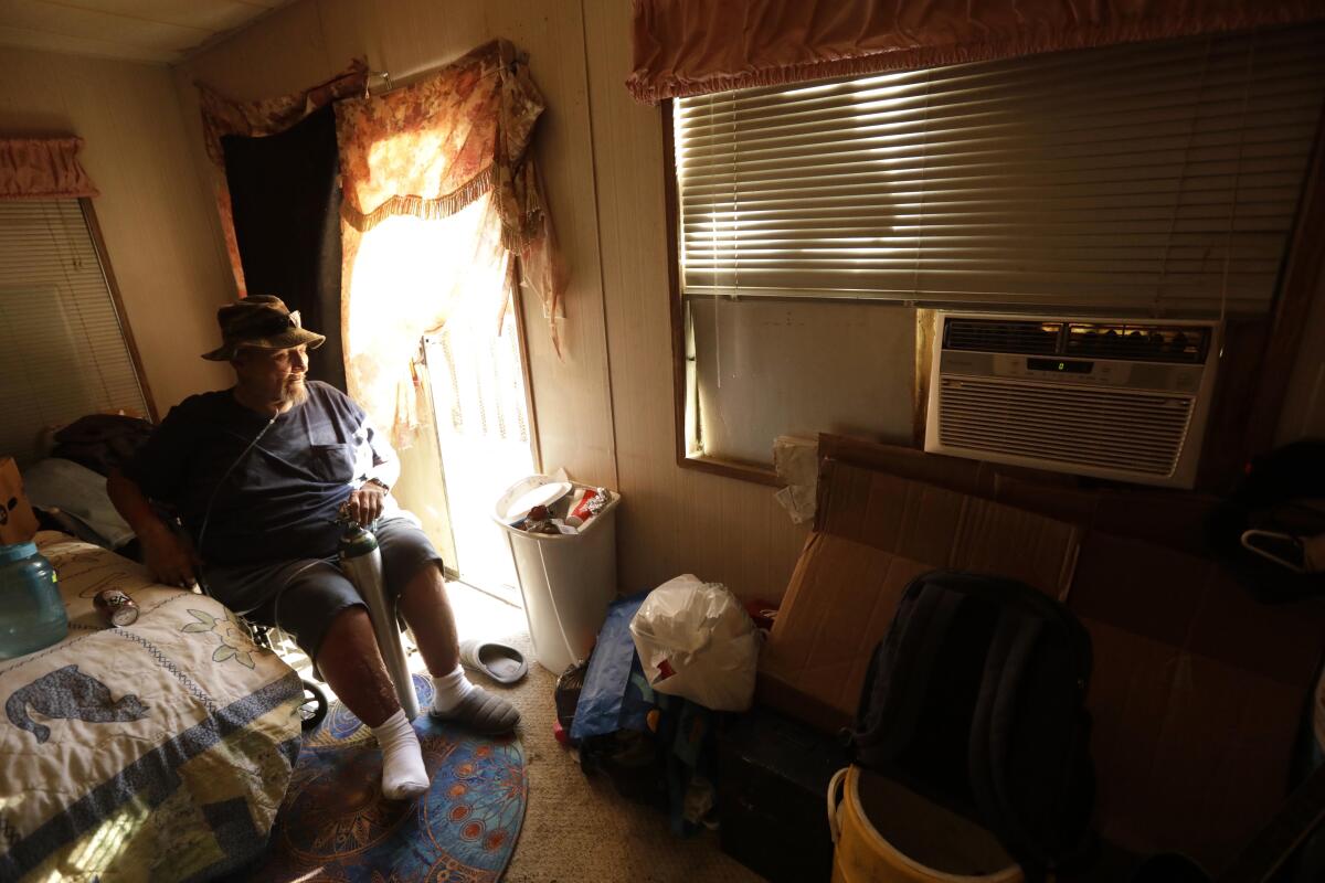 A resident of a trailer park in Desert Hot Springs sits near his air conditioner as he tries to cool down in May 2021. 